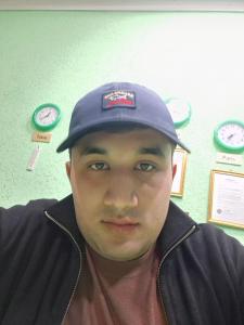 a man wearing a hat with clocks on the wall at Royal Garden in Bukhara