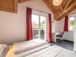 a bedroom with two beds and a desk and a window at Kipaji 3 in Kötschach