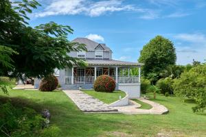 ein weißes Haus mit einer Veranda und einem Rasen in der Unterkunft Le Flamboyant in Saint-Louis