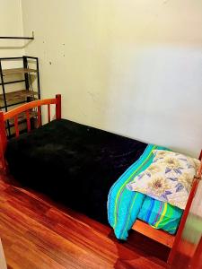 ein Bett mit einer schwarzen Decke auf einem Holzboden in der Unterkunft Arriendo a diario casa en pleno centro de Ovalle in Ovalle