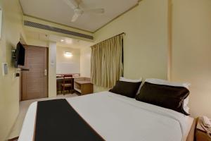 a bedroom with a large white bed and a desk at Collection O Pune Railway Station Formerly Kapil Residency in Pune