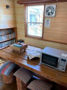 a wooden table with a microwave on top of it at Guesthouse PAW in Nagano