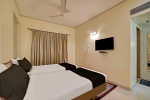 a bedroom with two beds and a flat screen tv at Collection O Pune Railway Station Formerly Kapil Residency in Pune