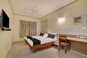 a bedroom with a bed and a desk and a television at Collection O Pune Railway Station Formerly Kapil Residency in Pune +17 photos
