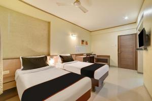 a hotel room with two beds and a television at Collection O Pune Railway Station Formerly Kapil Residency in Pune