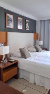 une chambre avec un grand lit blanc et une table dans l'établissement Varandas de PontaNegra - FLATS, à Natal