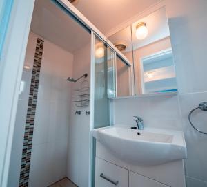 a white bathroom with a sink and a shower at Mollymook Beach getaway in Mollymook