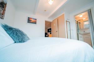a white bedroom with a large white bed at Mollymook Beach getaway in Mollymook