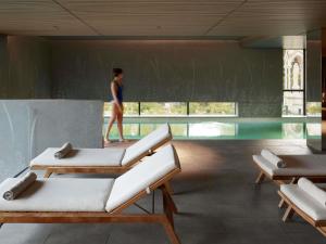 eine Person, die in einem Schwimmbad mit einer Person im Hintergrund spazieren geht in der Unterkunft Domaine de la Reine Margot Paris-Issy - MGallery Collection in Issy-les-Moulineaux