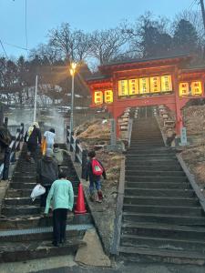 a group of people walking up the stairs to a temple at 蔵王ペンション kobaya in Kaminoyama +4 photos