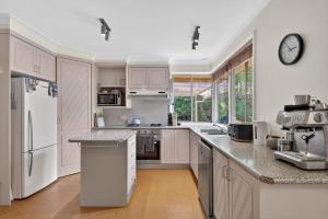 une cuisine avec des armoires blanches et une horloge au mur dans l'établissement Natures Haven Wentworth Falls with Sauna & Pool, à Wentworth Falls