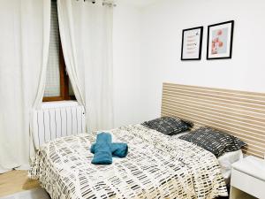 un animal en peluche bleu assis sur un lit dans l'établissement Élégant studio rénové Confort et tranquillité, à Saint-Quentin