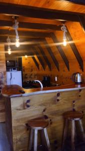 een keuken met een houten aanrecht met 2 krukken bij Chalé do lago in Campo Alegre