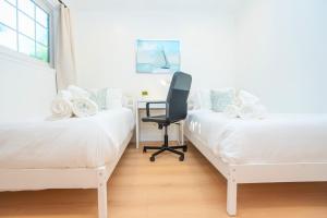 une chambre avec deux lits avec une chaise et un bureau dans l'établissement Spacious SJ 4BR Home Prime Location Near Everything, à San José