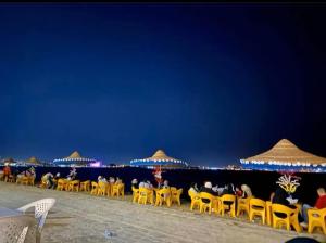 eine Gruppe von Stühlen und Sonnenschirmen am Strand in der Nacht in der Unterkunft قرية النورس in Ismailia