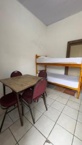 a room with two bunk beds and a table and chairs at Beira Mar Residencial in Capão da Canoa