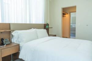 a bedroom with a white bed and a telephone at Chic 1-Bedroom w Ocean & Park Views in Panama City in Panama City