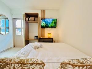 Schlafzimmer mit einem weißen Bett und einem TV an der Wand in der Unterkunft Hotel Casa Obed in Cartagena de Indias