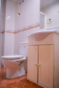a white bathroom with a toilet and a sink at Hostal Tarifa in Albaida