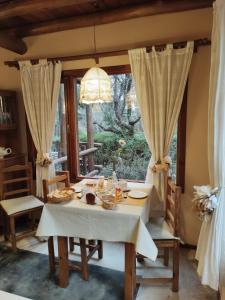 ein Esszimmer mit Tisch und Stühlen und einem Fenster in der Unterkunft Posada La Lucía in Villa General Belgrano