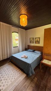 a bedroom with a large bed and a chandelier at Sítio Chamego - RJ in Engenheiro Paulo de Frontin