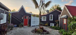 Eine Gruppe von Häusern mit einer Palme im Garten in der Unterkunft Ebony Cottage in Mangawhai