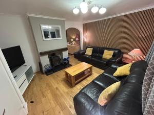 a living room with a black leather couch and a television at Glebeside House in Satley