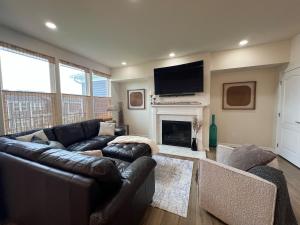un salon avec un canapé en cuir et une cheminée dans l'établissement Kensington Kickback QUICK Access to Ann Arbor, 