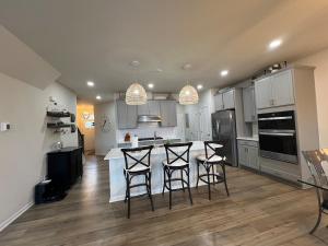 une cuisine avec des placards blancs et un îlot avec des tabourets de bar dans l'établissement Kensington Kickback QUICK Access to Ann Arbor, 