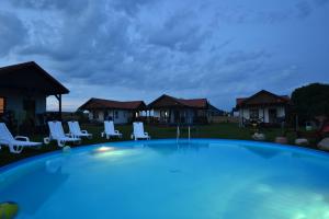 a large swimming pool with chairs and houses at Polne Domki in Darłowo