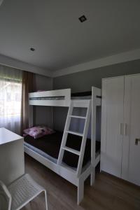 a white bunk bed in a room with a ladder at Polne Domki in Darłowo