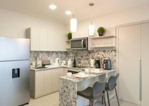 a kitchen with a counter with chairs and a refrigerator at Corporate Rental Studio with Scenic and Ocean View in Panama City