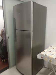 einem Kühlschrank aus rostfreiem Stahl neben einem Tisch in der Unterkunft Apartamento no centro de São Lourenço in São Lourenço