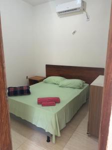 a bedroom with a bed with a green blanket and a fan at Casa Tunel in Pôrto de Pedras