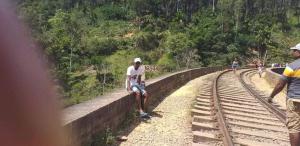 Un hombre sentado en un muro junto a las vías del tren en Indivilla, en Kalutara