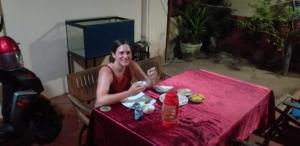 una mujer sentada en una mesa con un mantel rojo en Indivilla, en Kalutara