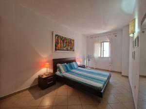 a bedroom with a bed with two lamps and a window at T2 Djadsal Bloco Laranja Perto da Praia e Centro in Santa Maria +7 photos