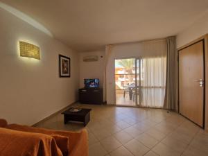 a living room with a couch and a tv and a table at T2 Djadsal Bloco Laranja Perto da Praia e Centro in Santa Maria