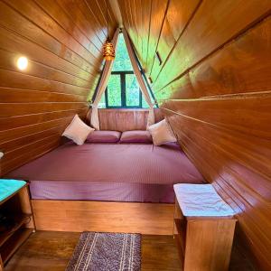 Una cama pequeña en una habitación de madera con ventana. en Eco Cabana Bellwood Kandy, en Nikawatawana 15 fotos más