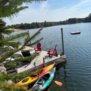 two kayaks are parked at a dock on a lake at Tait Lake Retreat - Luxury Lakeside Home in Turriff