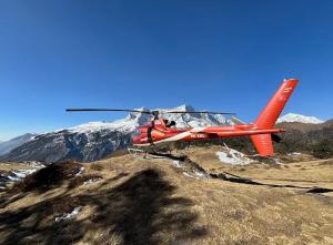 a red helicopter is flying over a mountain at Mountain Flight Everest in Chaunrikharka