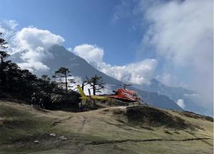 a helicopter parked on top of a hill with a mountain at Mountain Flight Everest in Chaunrikharka