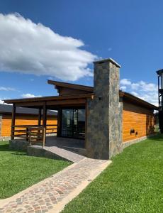 une maison avec une cheminée en pierre dans l'herbe dans l'établissement San Yucac Relax, à Los Reartes