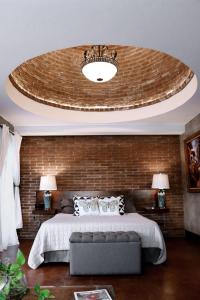 une chambre avec un grand lit et un mur de briques dans l'établissement Suite Mediterranea Valle de Gpe WiFi BBQ & Pool, à Villa de Juárez