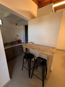 eine kleine Küche mit einem Holztisch und zwei Hockern in der Unterkunft Cocheras Ezeiza Victoria in Ezeiza