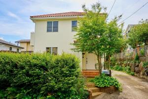 une maison blanche avec un arbre dans une cour dans l'établissement Atami Regalo - Vacation STAY 62917v, à Atami