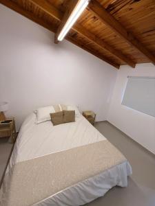 ein Schlafzimmer mit einem weißen Bett und einer Holzdecke in der Unterkunft Cocheras Ezeiza Victoria in Ezeiza