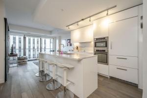 eine Küche mit weißen Schränken und einer Theke mit Stühlen in der Unterkunft Cozy 2BR Apt with Gym and Cinema near Pier 21 in Halifax