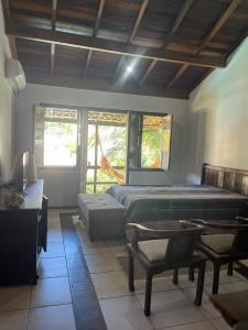 a bedroom with a bed and a desk and windows at Residencial Casa Amarela in Garopaba