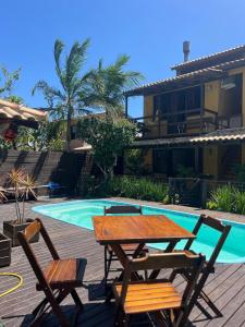 a picnic table and chairs next to a swimming pool at Residencial Casa Amarela in Garopaba